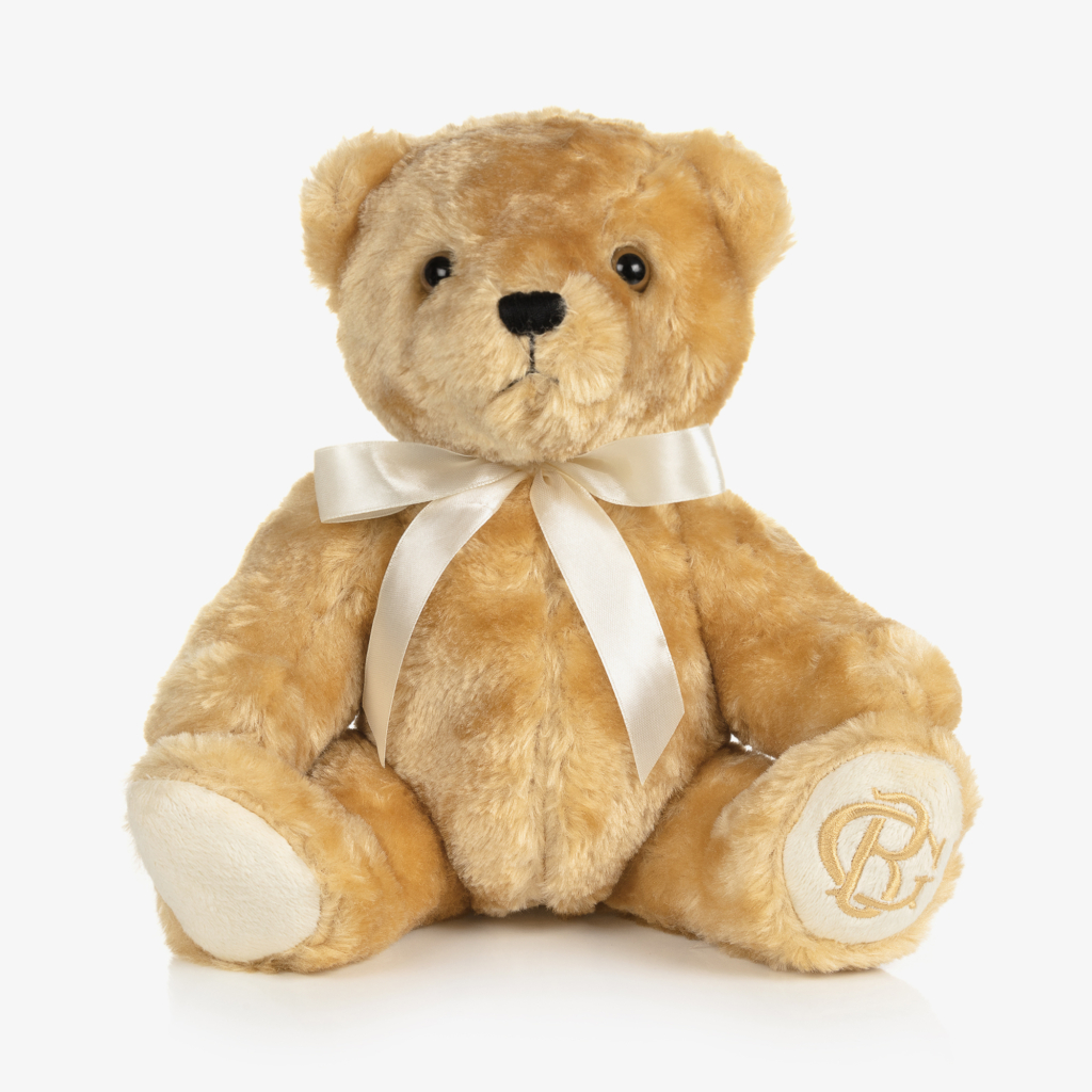 A golden furred teddy bear with a cream ribbon tied around it's neck