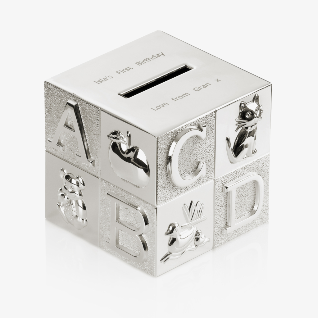 A silver cube money box with letters and different symbols embossed on to the outside.